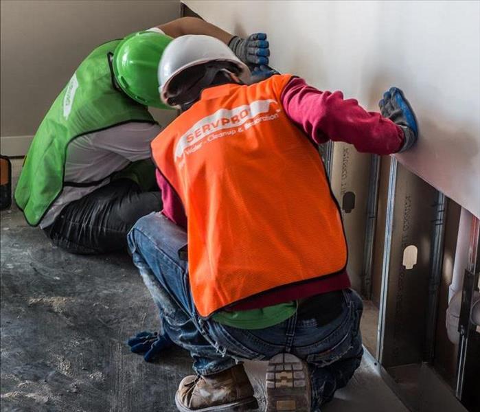 Servpro workers repairing wall