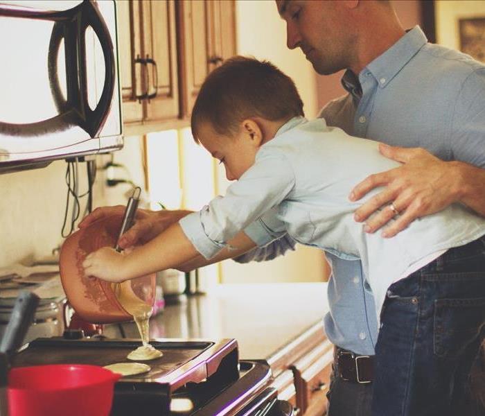 Man and child pouring pancake mix on a pan