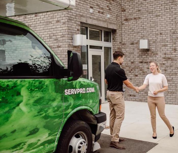 Male and Female shaking hands infront of green SERVPRO truck